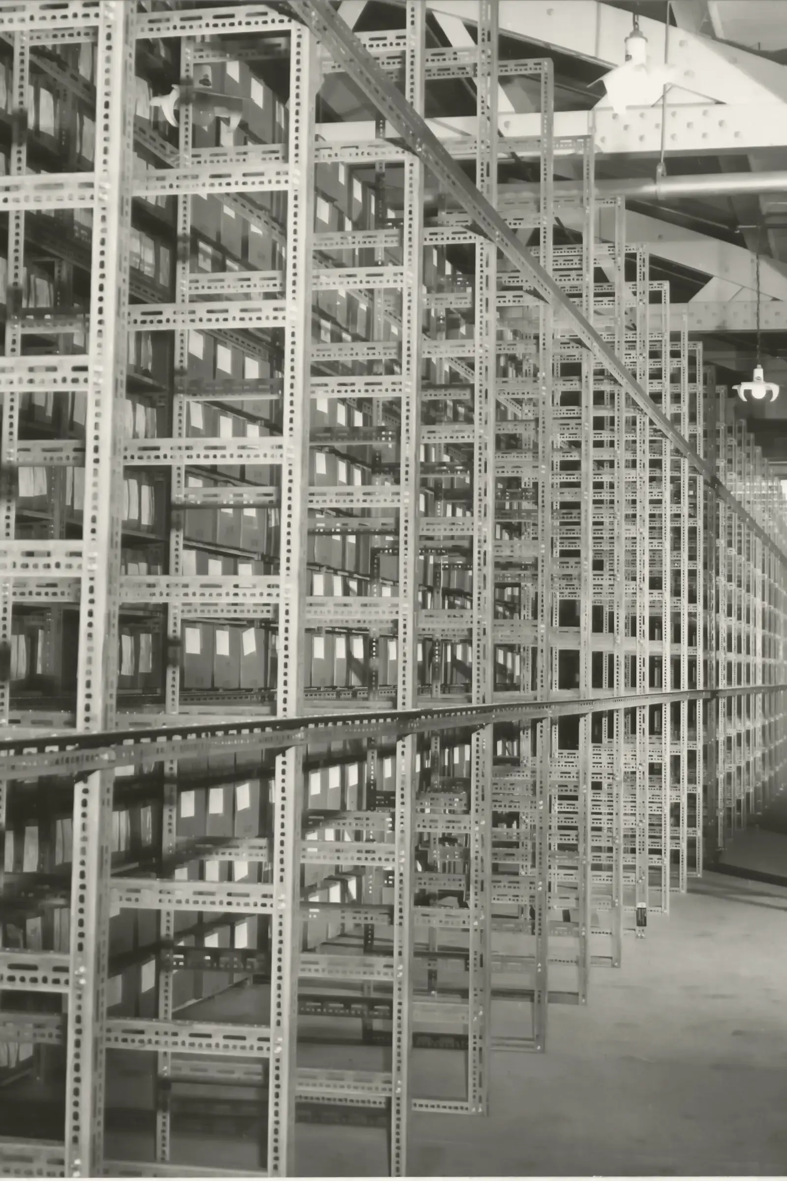 Rayonnage d’archives en enfilade : la répétition des travées file vers le fond de la salle.